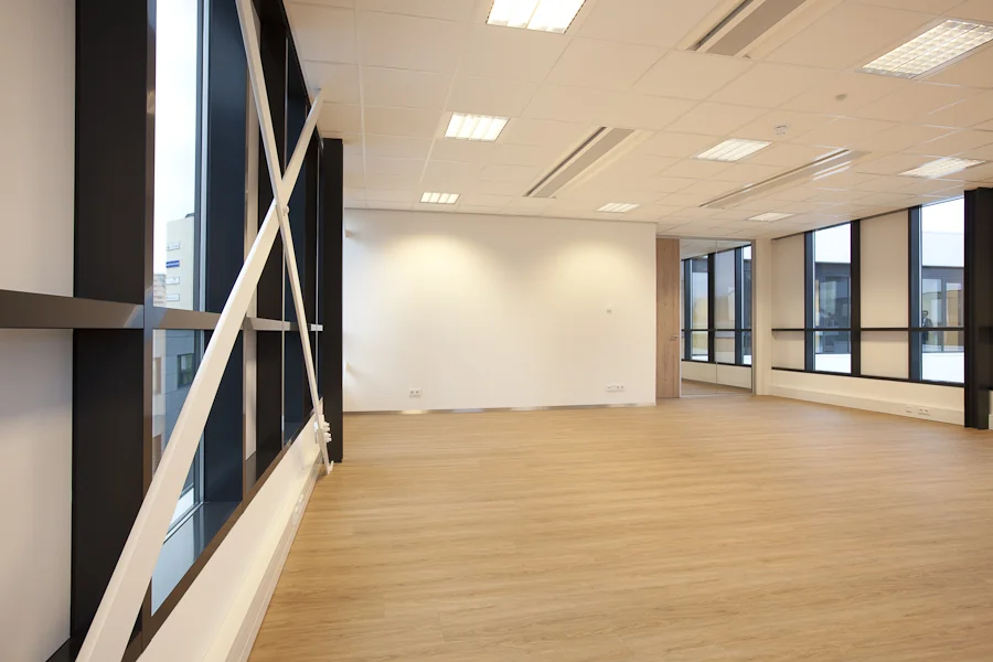 Lichte, lege kantoorruimte aan de De Boelelaan met grote ramen en een houten vloer.